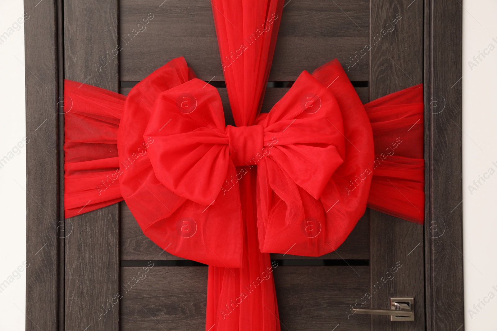 Photo of Wooden door with beautiful red bow. Christmas decoration