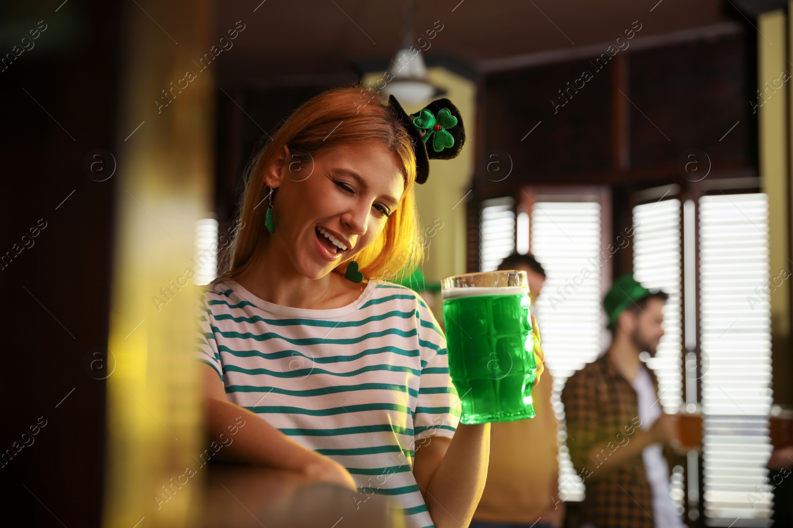 Photo of Young woman with glass of green beer in pub. St. Patrick's Day celebration