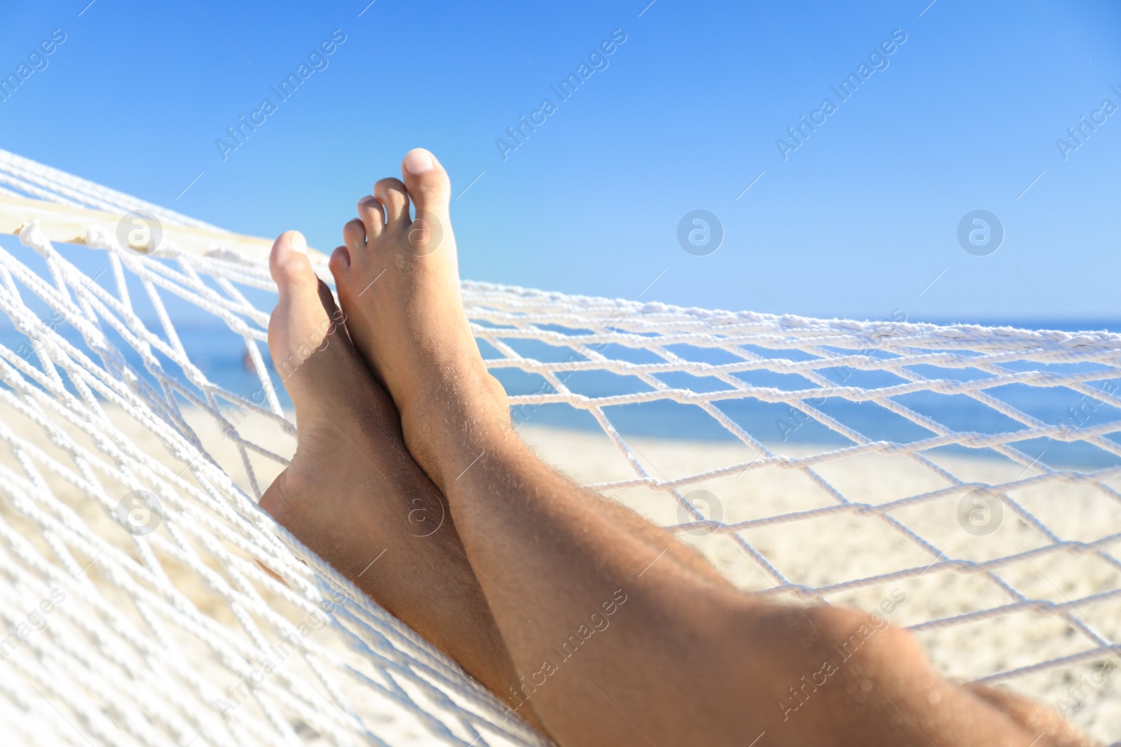 Photo of Man relaxing in hammock on beach, closeup