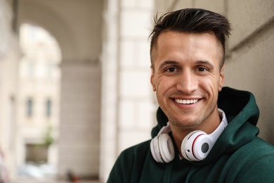 Photo of Portrait of handsome young man with headphones outdoors. Space for text