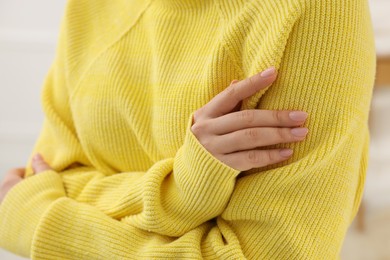 Photo of Woman touching sweater made of soft yellow fabric, closeup