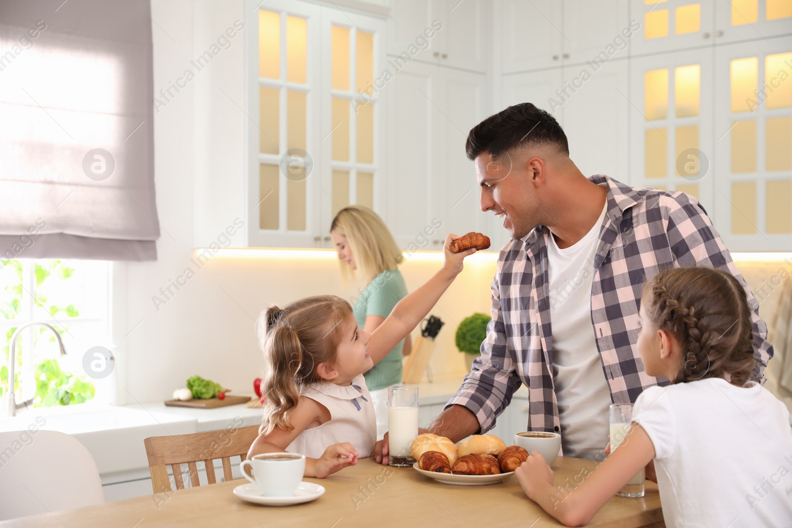 Photo of Happy family eating together at table in modern kitchen