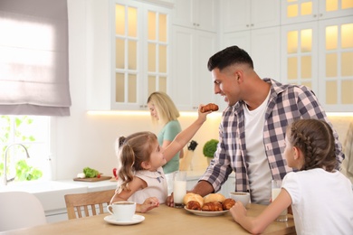 Happy family eating together at table in modern kitchen