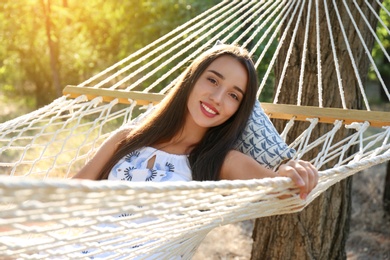 Young woman resting in comfortable hammock at green garden