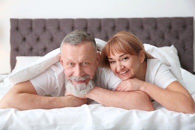 Mature couple together under blanket in bed at home