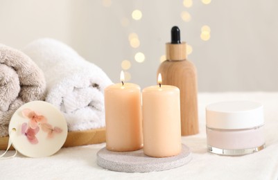 Photo of Spa composition. Burning candles and personal care products on soft white surface