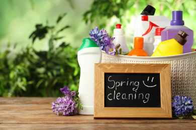 Photo of Composition with Spring Cleaning sign, flowers and detergents on wooden table