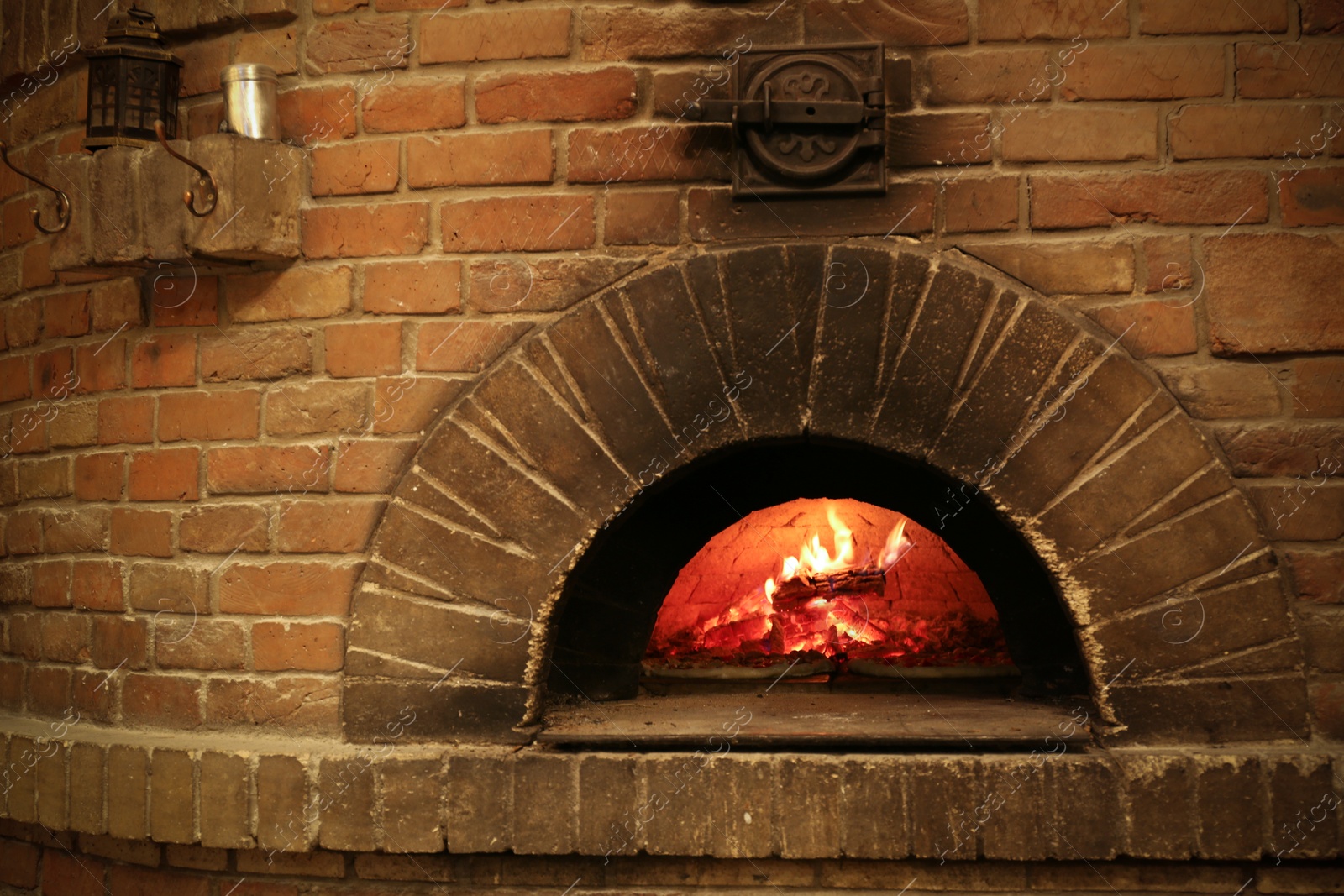 Photo of Brick oven with burning firewood and pizzas indoors