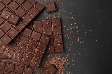 Pieces and shavings of tasty chocolate bars on grey table, flat lay. Space for text