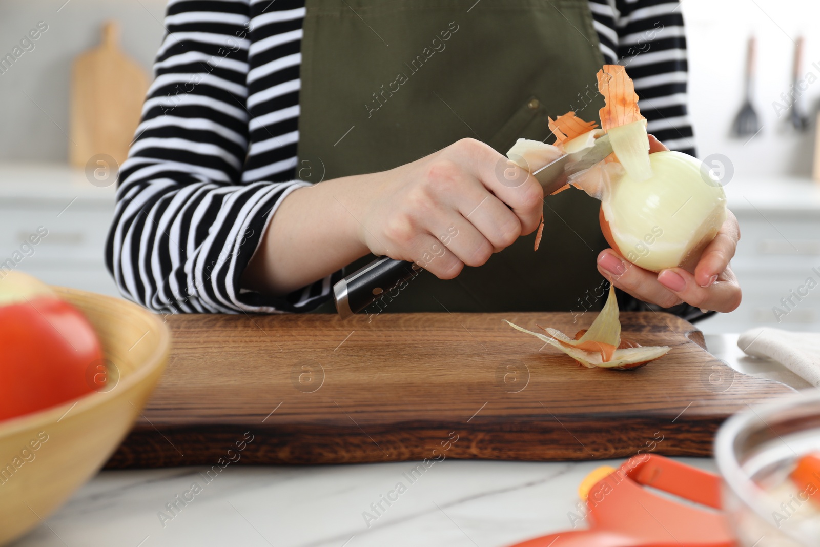 Photo of Woman peeling fresh onion with knife at white marble table indoors, closeup