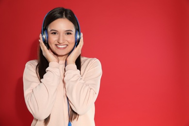 Photo of Attractive young woman enjoying music in headphones on color background. Space for text