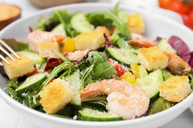 Photo of Delicious salad with croutons, cucumber and shrimp served on table, closeup