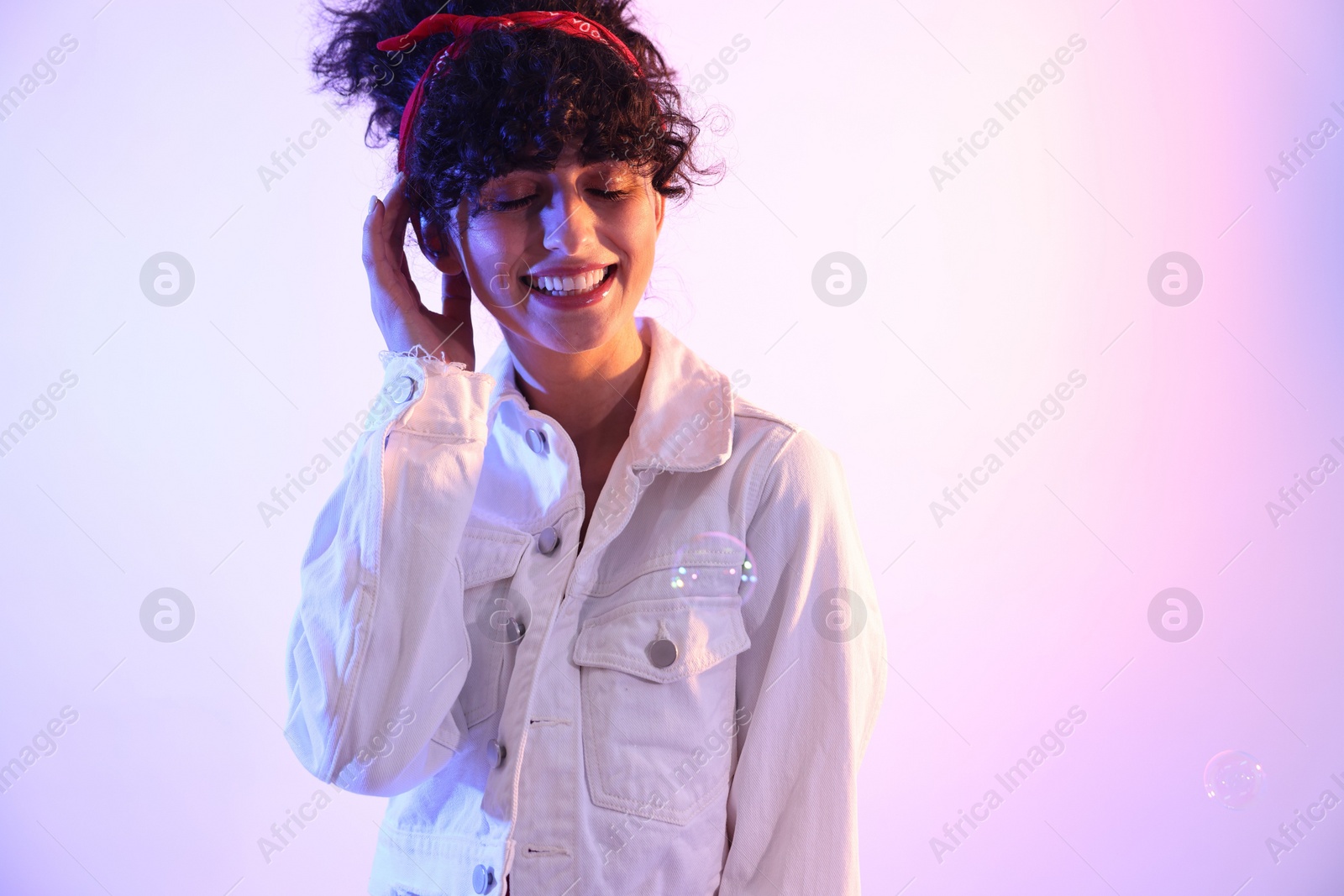 Photo of Beautiful young woman and bubbles on color background in neon lights. Space for text
