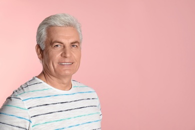 Photo of Mature man with healthy teeth on color background. Space for text
