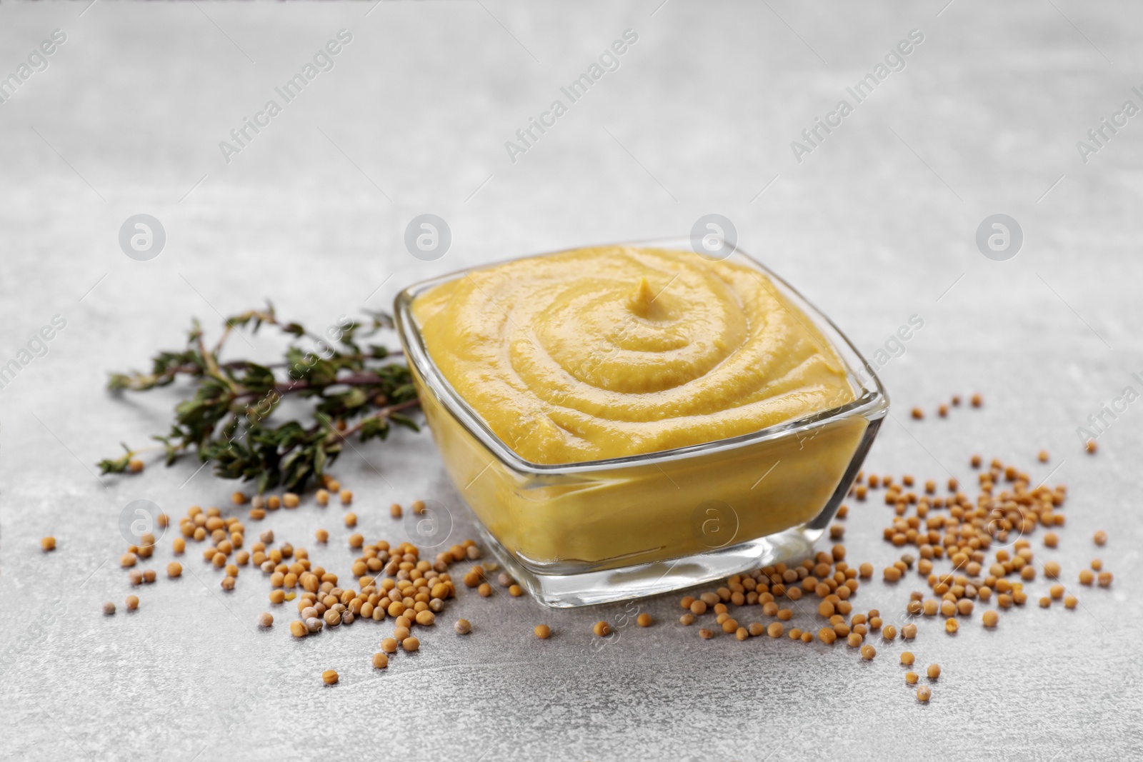 Photo of Delicious mustard, seeds and dry thyme on light grey table