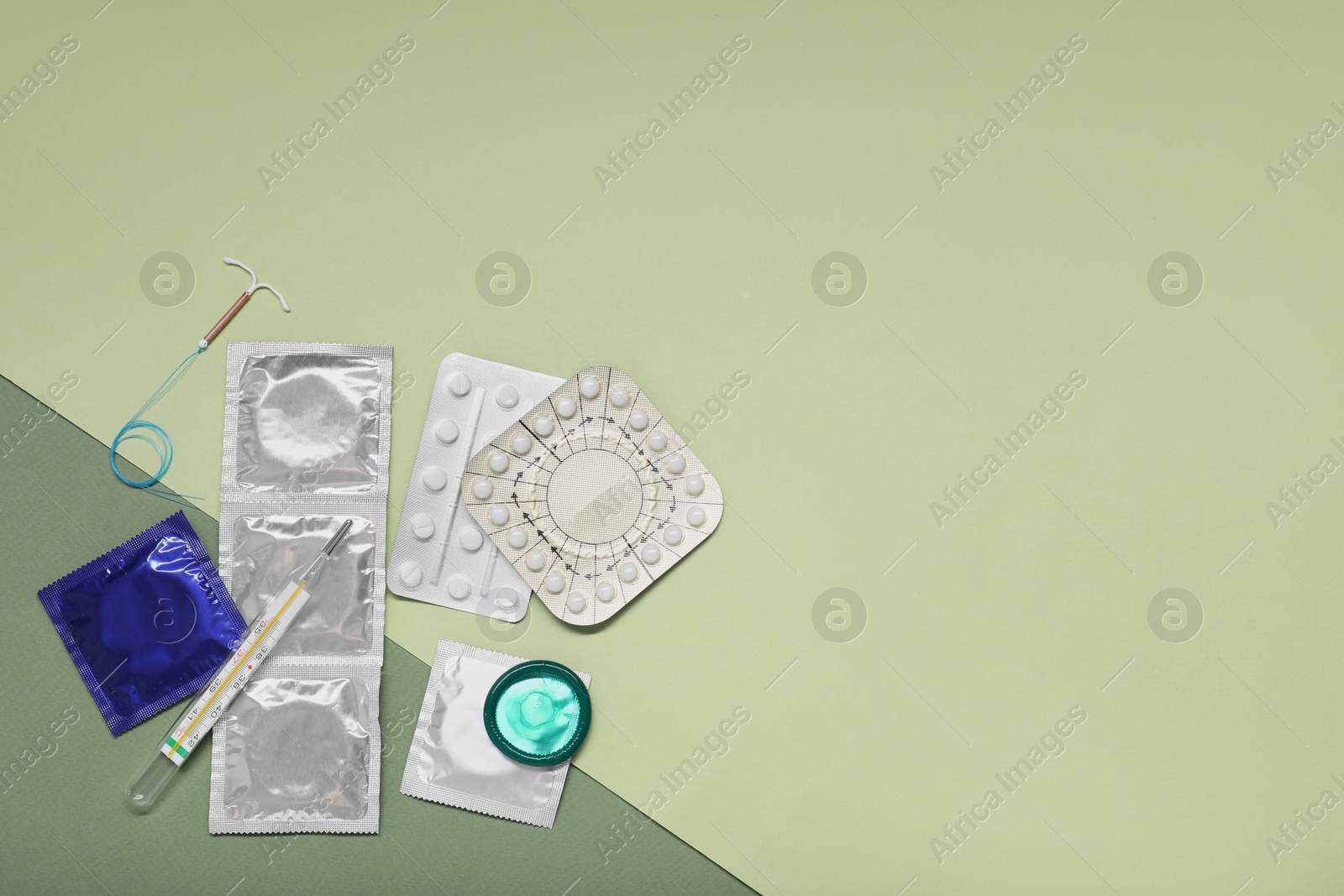 Photo of Contraceptive pills, condoms, intrauterine device and thermometer on color background, flat lay with space for text. Choice of birth control method