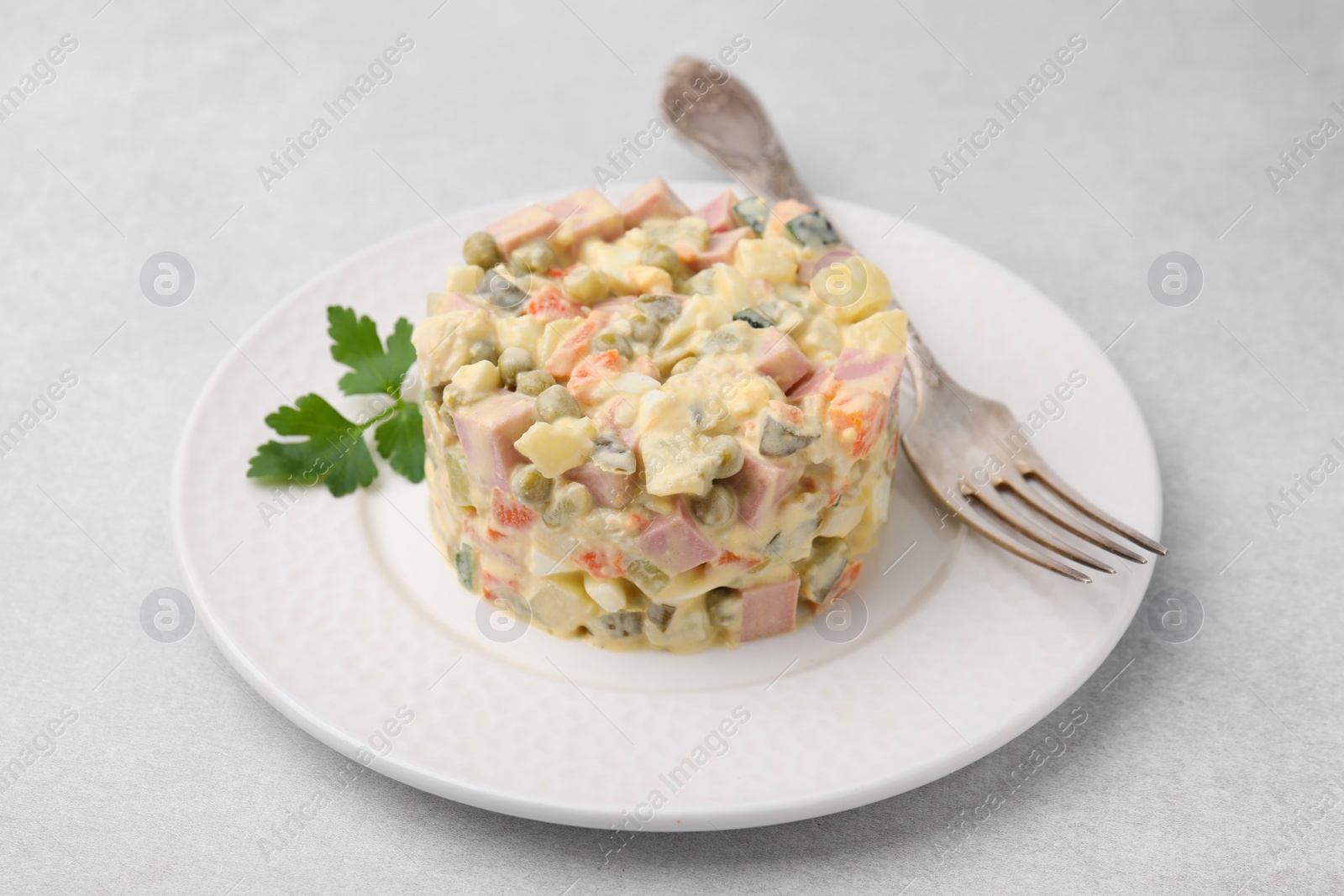 Photo of Tasty Olivier salad with boiled sausage and fork on light table