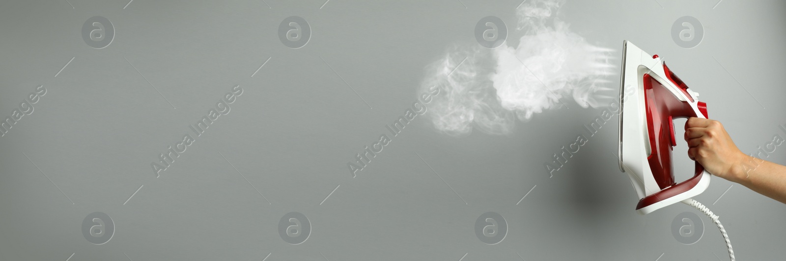 Image of Woman with iron on light grey background, closeup. Banner design with space for text