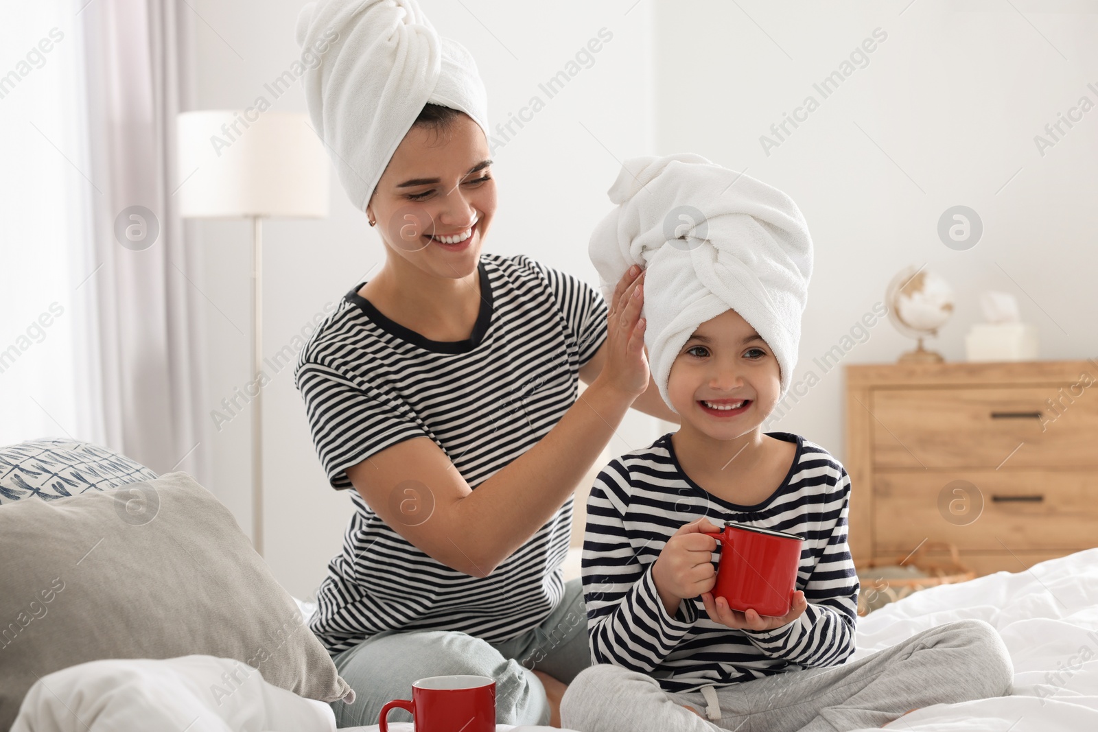 Photo of Young mother and her daughter spending time together on bed at home