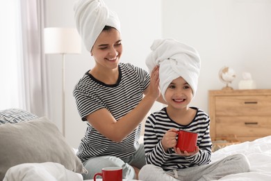 Young mother and her daughter spending time together on bed at home