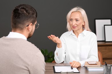 Woman having conversation with man at wooden table in office. Manager conducting job interview with applicant