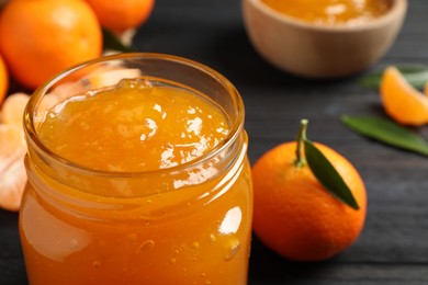 Tasty tangerine jam in glass jar on table, closeup. Space for text