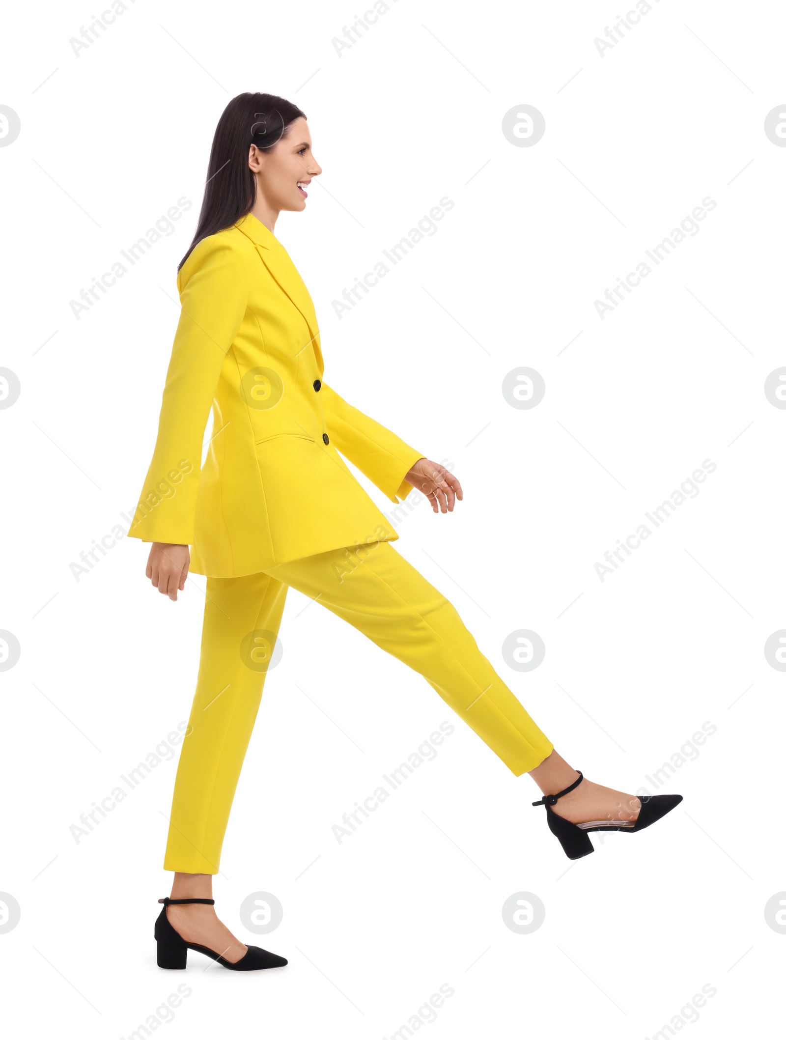 Photo of Beautiful businesswoman in yellow suit walking on white background