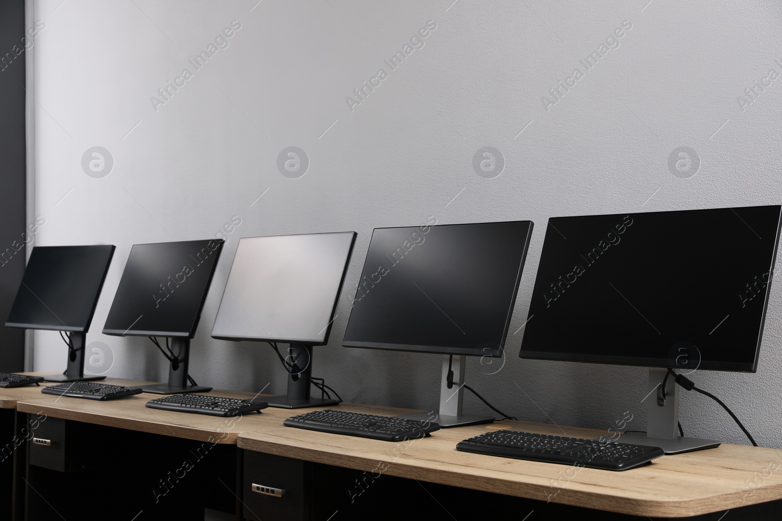 Photo of Open office interior. Modern workplaces with computers near light grey wall