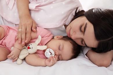Photo of Young mother resting near her sleeping baby on bed