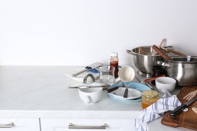 Photo of Many dirty utensils and dishware on countertop in messy kitchen. Space for text
