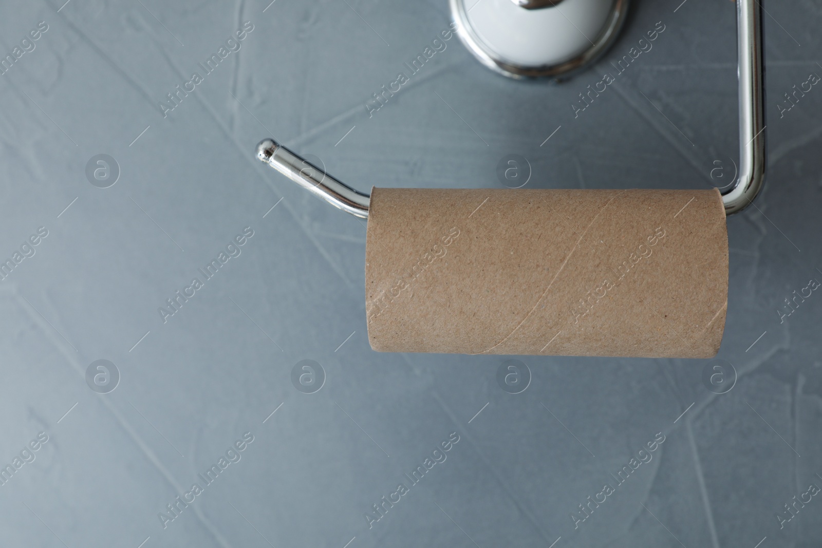 Photo of Holder with empty toilet paper roll on gray wall