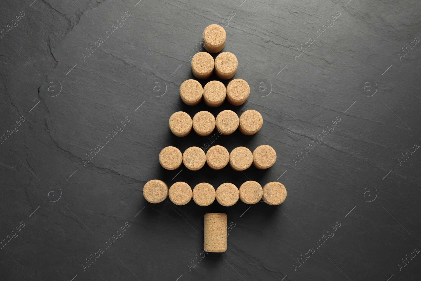 Photo of Christmas tree made of wine corks on dark stone background, top view