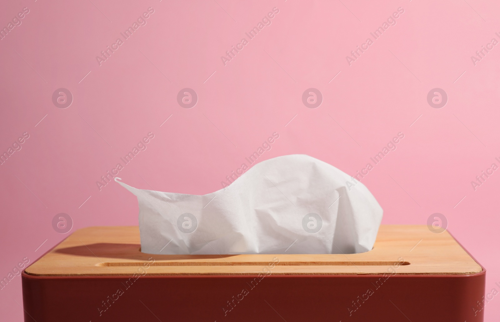 Photo of Holder with paper tissues on pink background, closeup