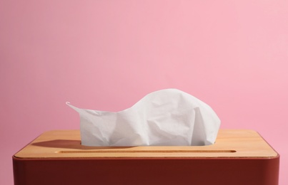 Photo of Holder with paper tissues on pink background, closeup