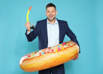 Photo of Funny businessman with bright inflatable ring on blue background