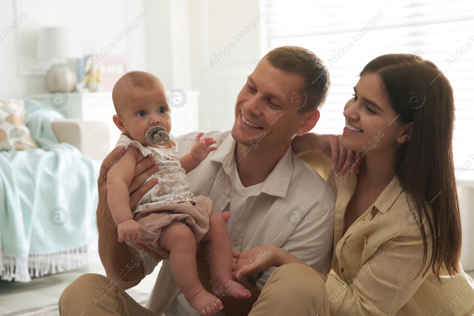 Photo of Happy couple and their cute little baby with pacifier at home