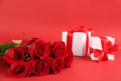 Photo of Beautiful roses and gift boxes on red background, space for text. St. Valentine's day celebration