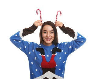 Young woman in Christmas sweater holding candy canes on white background