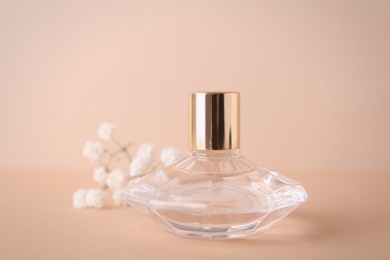 Photo of Beautiful bottle of aromatic perfume near flowers on color background