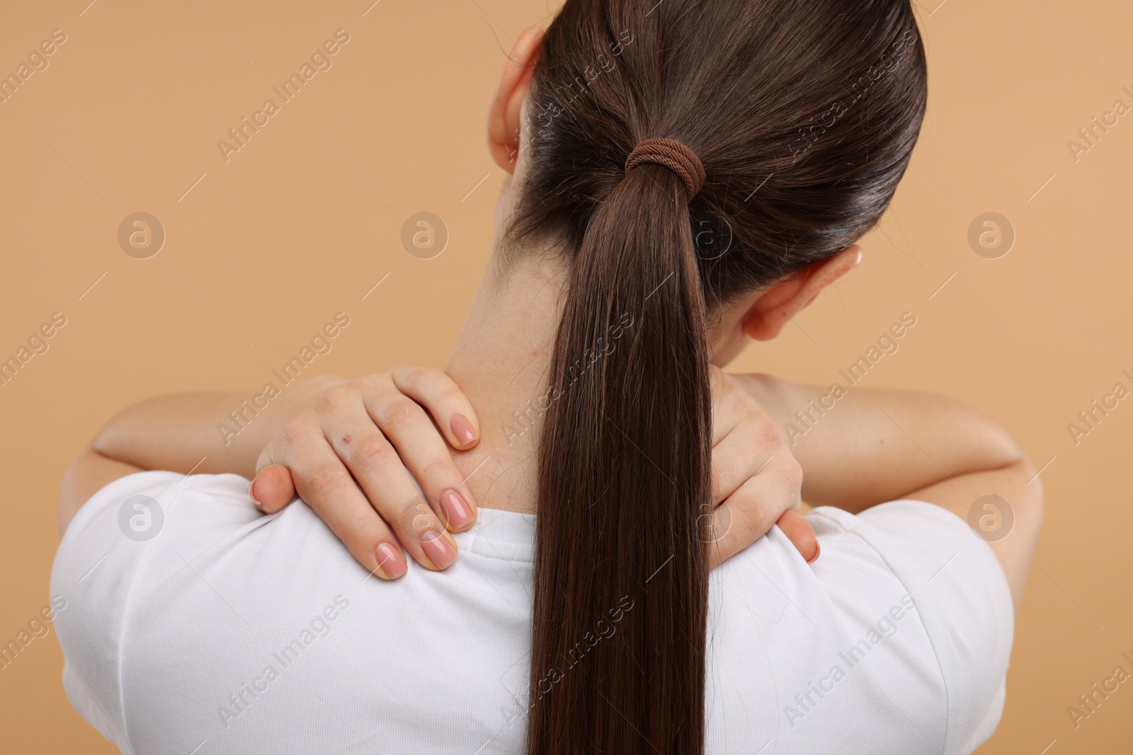 Photo of Woman touching her neck on beige background, back view
