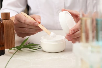 Dermatologist developing cosmetic product at light marble table, closeup