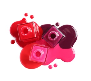 Photo of Spilled different nail polishes with bottles on white background, top view