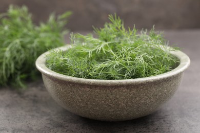 Bowl of fresh dill on grey table, closeup