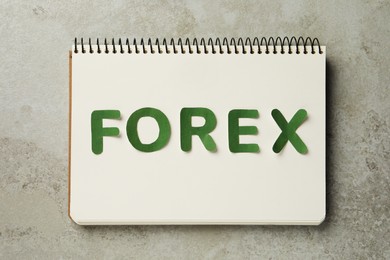 Photo of Notebook with word Forex made of green letters on grey table, flat lay