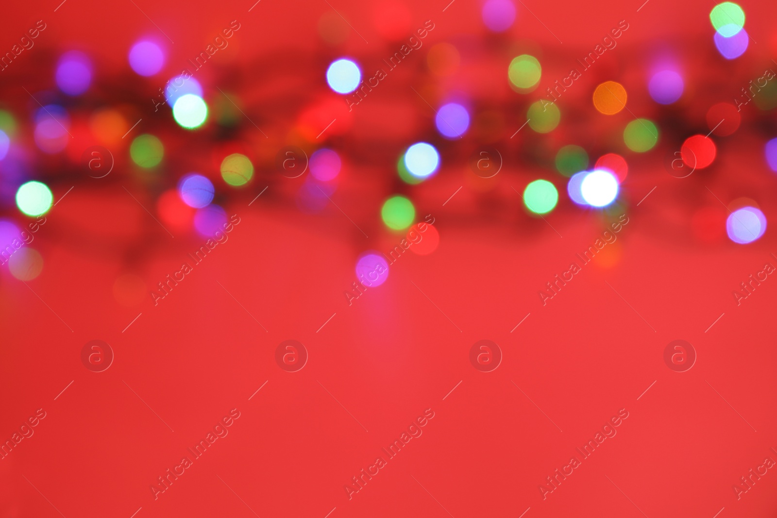 Photo of Blurred view of glowing Christmas lights on color background, top view