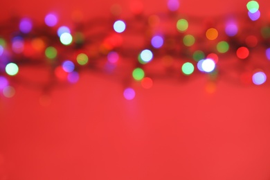 Photo of Blurred view of glowing Christmas lights on color background, top view