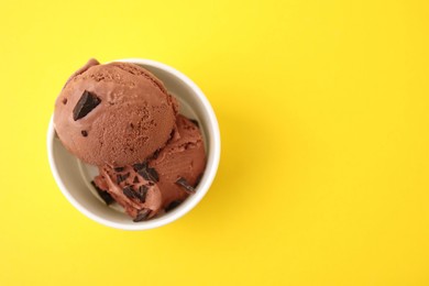 Photo of Cup with tasty chocolate ice cream on yellow background, top view. Space for text