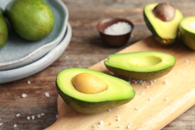 Photo of Wooden board with cut avocados on table