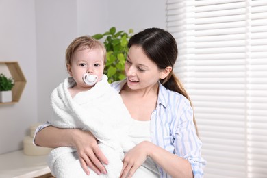 Photo of Mother wrapping her cute little baby with towel after bathing at home