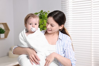 Mother wrapping her cute little baby with towel after bathing at home